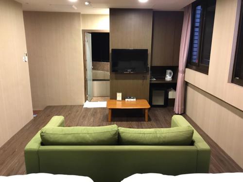 a living room with a green couch and a table at Every Day Hot Spring Hotel in Jiaoxi