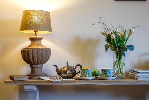 a table with a lamp and cups and a vase of flowers at Botanica in Dánszentmiklós