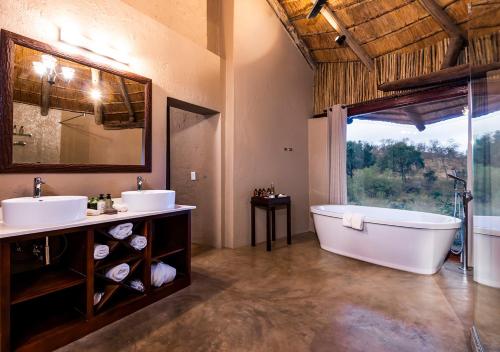 baño con 2 lavabos, bañera y ventana en aha Makalali Private Game Lodge, en Makalali Game Reserve