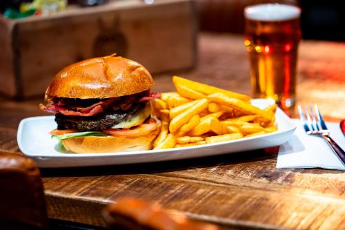 a sandwich and french fries on a plate with a glass of beer at Kick Ass Greyfriars (18+) in Edinburgh