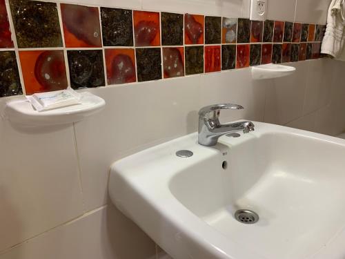a white sink in a bathroom with colorful tiles on the wall at Terrazas de Colón in Colón