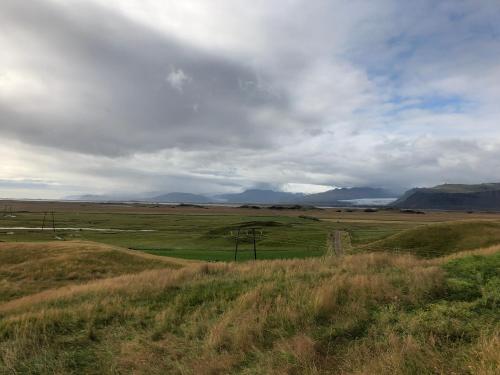 a field of grass with mountains in the background at Miðsker 1 in Höfn