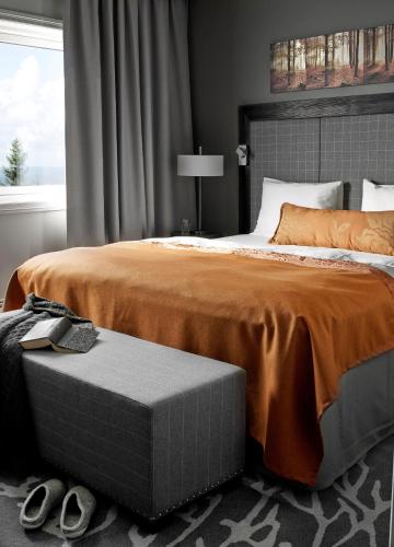 a bedroom with a large bed with an orange comforter at Soria Moria Hotell in Oslo