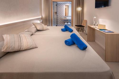 a large bed with blue pillows on top of it at Hotel Alhambra in Santa Susanna