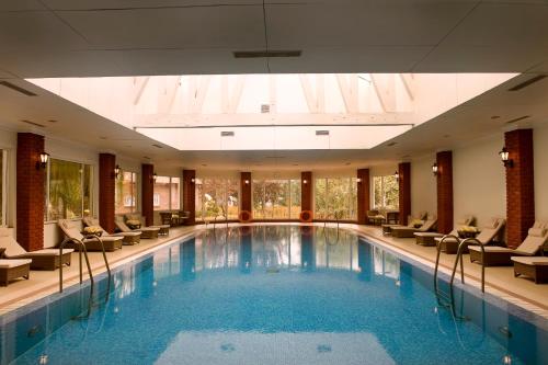 a pool in a hotel with chairs and a large room at The LaLit Grand Palace Srinagar in Srinagar