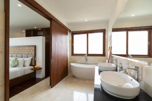 a bathroom with two sinks and a tub and a bed at Athaya Ubud in Ubud