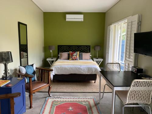 ein Schlafzimmer mit einem Bett und einer grünen Wand in der Unterkunft Frida’s Place - Quiet in Stellenbosch Central in Stellenbosch