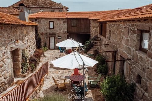 an outdoor patio with tables and umbrellas in a building at Casa de Louredo in Paredes