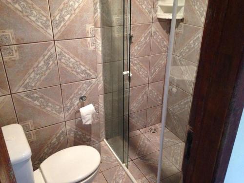 a bathroom with a toilet and a glass shower at Pousada e Restaurante Dona Siroba in Morretes