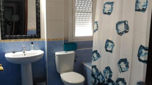 baño azul y blanco con aseo y lavamanos en Apartamento Los conquistadores., en Sanlúcar de Barrameda