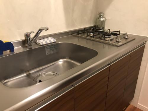 a stainless steel sink in a kitchen with a stove at Local Hakata apartment No9 in Fukuoka