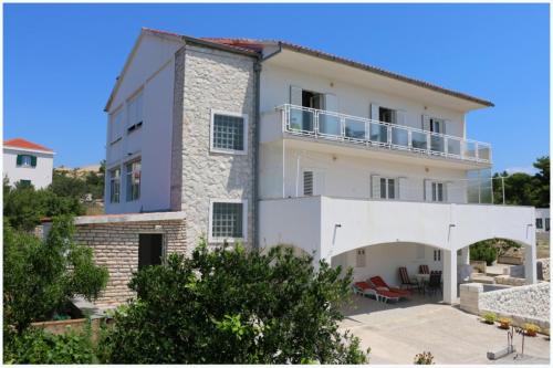 a large white building with a balcony at Apartmani Slavka in Primošten