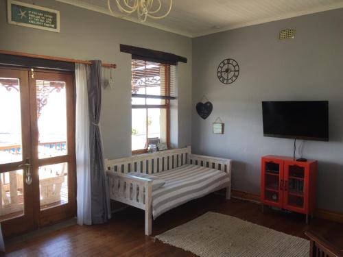 a living room with a crib and a tv on the wall at Sea View Charming Stone House in Mossel Bay