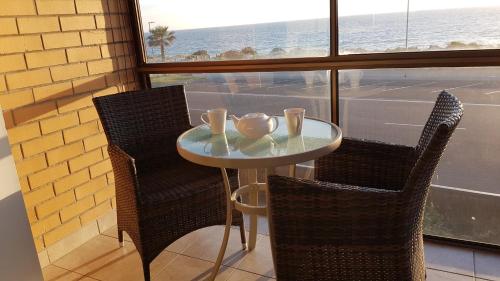 a table with two chairs and a table with two cups at Acushla Accommodation Esplanade Living Self Check-In Self Check-Out in Adelaide