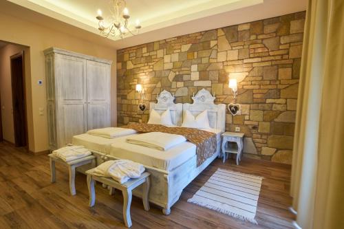 a bedroom with two beds and a stone wall at Takler Kúria in Szekszárd