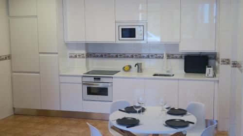 a white kitchen with a table and chairs with wine glasses at Apartamento Palacio Azcárate Calle San Isidro in Ezcaray
