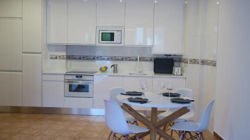 a kitchen with white cabinets and a table and chairs at Apartamento Palacio Azcárate Calle San Isidro in Ezcaray