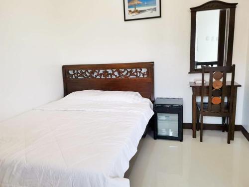 een slaapkamer met een bed met witte lakens en een spiegel bij MJ Pension House in Talisay