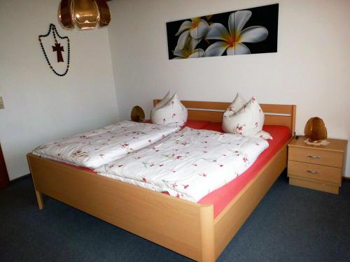 1 dormitorio con cama de madera con sábanas y almohadas blancas en Ferienwohnung Kraus, en Langdorf