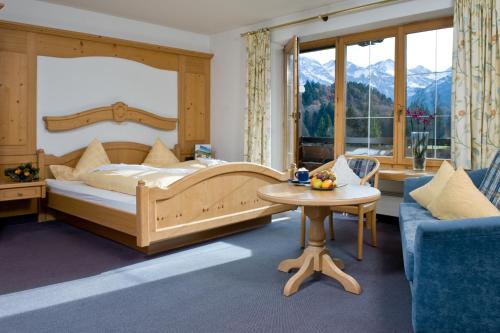 オーベルストドルフにあるAlpengasthof Hotel Schwandのベッドルーム1室(ベッド1台、テーブル、ソファ付)