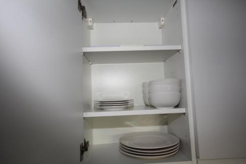 a white cabinet with plates and bowls in it at Holden Court Apartments -Apt 4 in West Drayton