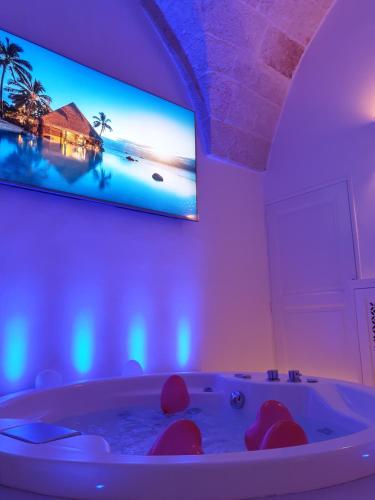 a bathroom with a tub with a tv on the wall at Christian's Suites & Spa in Fasano