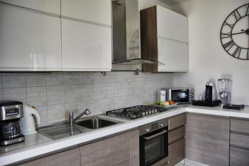 a kitchen with white cabinets and a sink and a clock at Casa la Pianca in Menaggio
