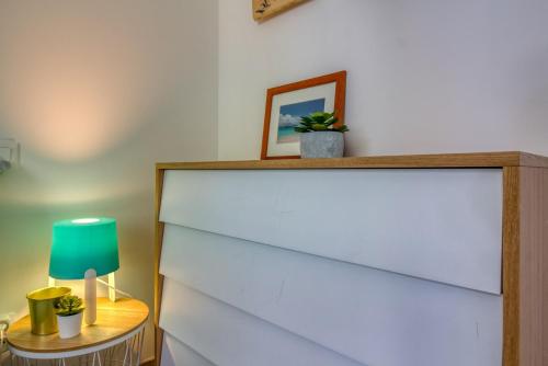 a white dresser with a green lamp on a table at L Her Beau d Hier in LʼÉpine