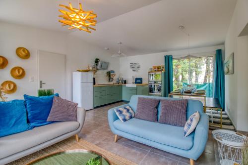 a living room with two blue couches and a kitchen at L Her Beau d Hier in LʼÉpine
