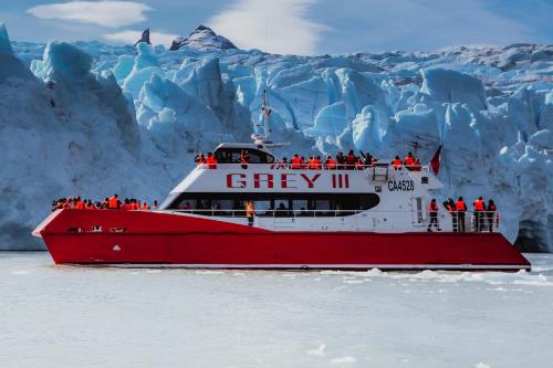 a group of people on a boat in front of a glacier at Hotel Lago Grey in Torres del Paine
