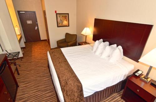 a hotel room with a large bed and a chair at Cobblestone Inn & Suites - Clarion in Clarion