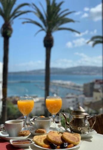 a table with two glasses of orange juice and biscuits at Hôtel Rembrandt in Tangier