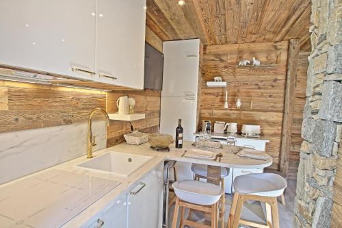 a kitchen with a sink and a counter with stools at Résidence rond point des pistes accès direct funiculaire exposé sud in Tignes