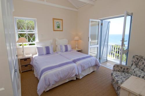 a bedroom with a bed and a balcony with the ocean at Felsensicht Holiday Home in Simonʼs Town