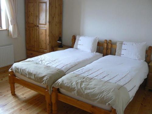 Duas camas num quarto com lençóis e almofadas brancos em Groff Cottage em Toormakeady