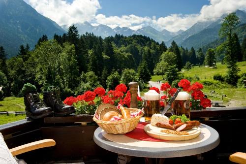 a table with food and beer on a balcony with mountains at Alpengasthof Hotel Schwand in Oberstdorf