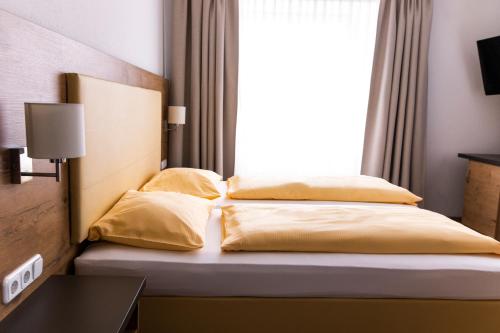 a bedroom with a bed with yellow sheets and a window at ZUM ZIEL Hotel & Restaurant Grenzach-Wyhlen bei Basel in Grenzach-Wyhlen