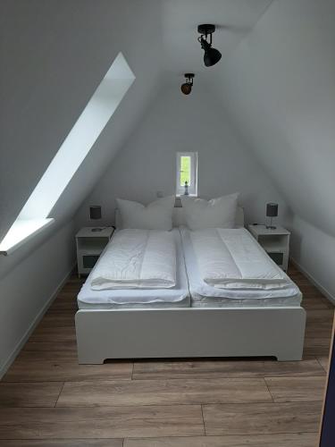 ein weißes Bett in einem Zimmer mit Dachgeschoss in der Unterkunft Steuerbord in Wangerland