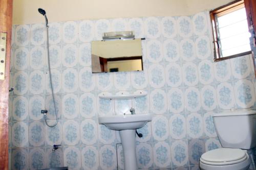 a bathroom with a sink and a toilet and a mirror at ASSOUKA Eco-Village du lac Nokoué in Abomey-Calavi