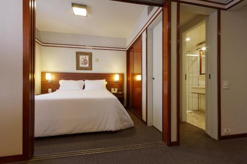 1 dormitorio con 1 cama blanca grande y espejo en Bristol The Time Berrini, en São Paulo