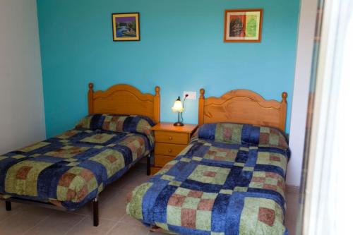 2 camas en una habitación con paredes azules en APARTAMENTO TURISTICO ACEDO, en Acedo