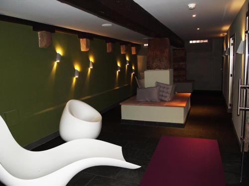 a living room with a green wall and a white chair at Logis Hôtel Ettenheim in Strasbourg