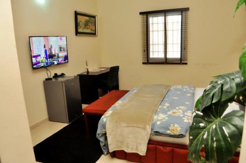 a room with a bed and a desk with a television at J Gibson Hotel in Lagos