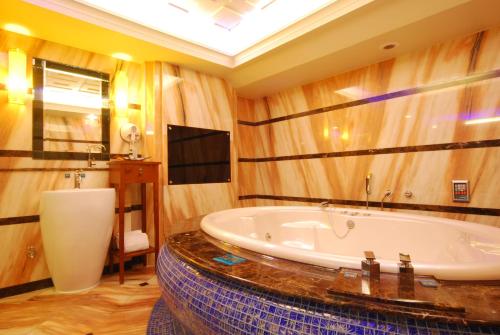 a large bathroom with a tub and a television in it at Mucha Motel in Kaohsiung