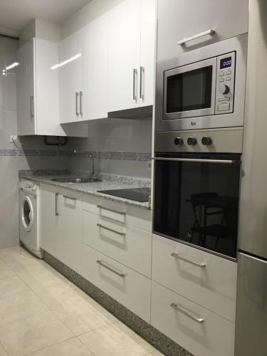 een keuken met witte kasten en een magnetron bij Apartamento Lua in Milladoiro