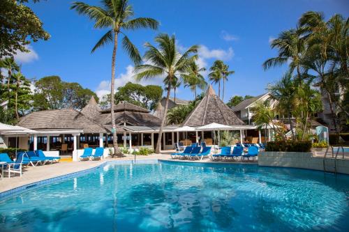 una piscina en un complejo con sillas azules y palmeras en The Club Barbados - All Inclusive - Adults Only, en Saint James