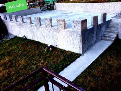 a concrete retaining wall with a fence in the grass at Nikolo Inn in Stepantsminda