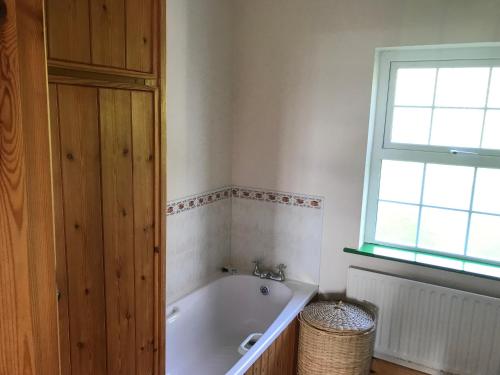 uma casa de banho com uma banheira e uma janela em Groff Cottage em Toormakeady