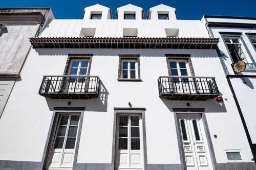 a white building with balconies on the side of it at Ilha Hostel & Suites in Ponta Delgada