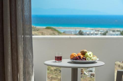 a table with a bowl of fruit and a glass of wine at Naxos Luxury Villas in Mikri Vigla